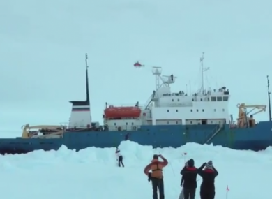 Passengers watch as a helicopter flies over the stranded ship.