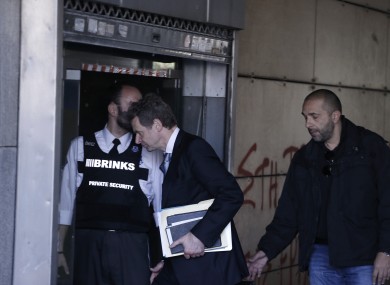 International Monetary Fund mission chief Poul Thomsen, center, escorted by a Greek plain clothed police man, enters the Greek Ministry of Finance in central Athens.