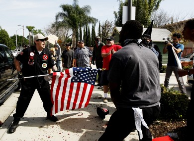 A Ku Klux Klansman, left, uses an American flag to fend off angry counter protesters.