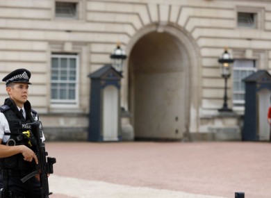 Armed police forces guard the entrance of Buckingham Palace in London today.
