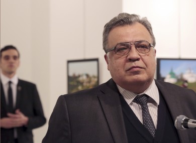 Andrei Karlov, the Russian Ambassador to Turkey, speaks at a photo exhibition in Ankara with the gunman behind him.
