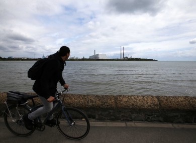 A cyclist glaces at the Poolbeg incinerator plant from the promenade.