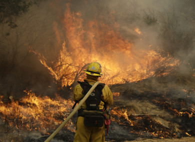 Fresno firefighter Peter Lopez holds a water hose as he monitors a backburn while fighting a wildfire.