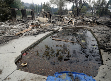 Debris and charred items litter a wildfire-ravaged home