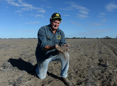 Farmer Rob Turnbull holds dry soil in his hands on what would have been a wheat field.