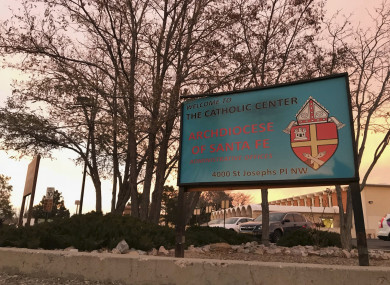 The sun sets on a sign in front of the Archdiocese of Santa Fe offices in Albuquerque, New Mexico