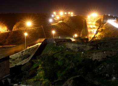 Floodlights from the US illuminate multiple border walls in Tijuana, Mexico.