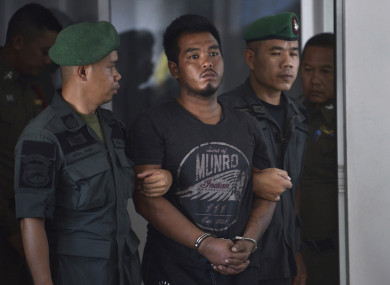 Ronakorn Romruen is escorted by police as he arrives at Koh Sichang police station