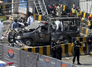 Pakistani security personnel surround a damaged police van in Lahore