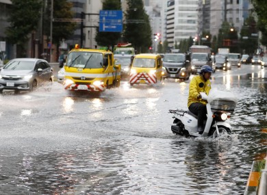A man rides a moped through a flooded street due to a typhoon in Tokyo