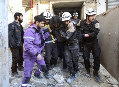 Photo released in February 2019 showing Syrian White Helmet members carrying an injured man from a building in Idlib hit by a shell from Syrian forces.