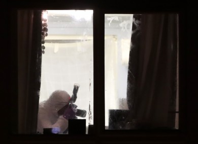 A PSNI forensic officer in a second floor apartment in a building on Kinnaird Close in Belfast, after the bodies of a man and woman were found yesterday.
