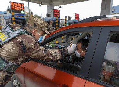 A security guard tests a driver’s temperature at a checkpoint at a highway toll gate in Wuhan on Thursday