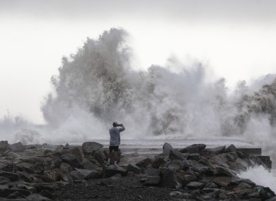 A man takes a snapshot of the waves hitting the breakwater in Barcelona, Spain