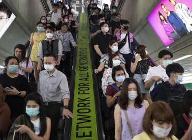 Commuters wear face masks to protect themselves from new virus at at skytrain station in Bangkok, Thailand.