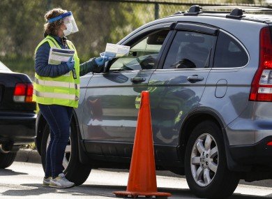 A healthcare worker handing out information to people waiting at a drive-through Covid-19 test centre in the US.