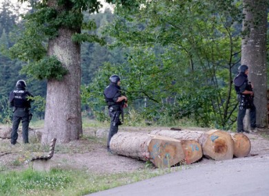 Police officers stay outside a wooded area on a road near Oppenau.