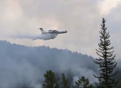 An amphibious aircraft releasing water to extinguish a fire in southern Siberia,