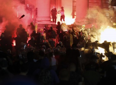 Protesters clash with riot police on the steps of the Serbian parliament in Belgrade last night.
