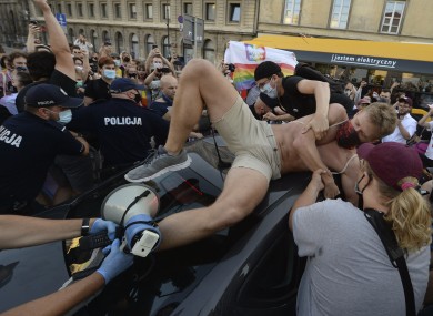 An activist climbs onto a police car while protesting in Warsaw.