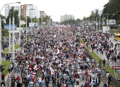 Protesters with old Belarusian national flags march during a protest in Minsk today.
