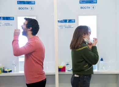 Two members of the public take an antigen test as part of a screening programme.