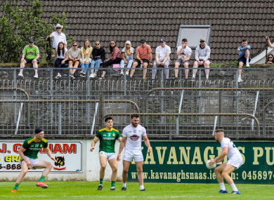 Fans without tickets watch the game from a wall outside the stadium.