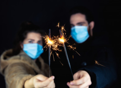 File photo of people wearing masks and holding sparklers
